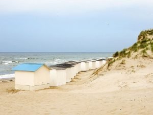 beach cabins along a white-sand beach with blue sea to the right and sand dunes to the left, best things to do on Texel island