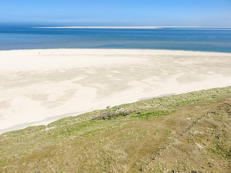 a view from a lighthouse to a white-sand beach and blue sea, view from the Texel lighthouse