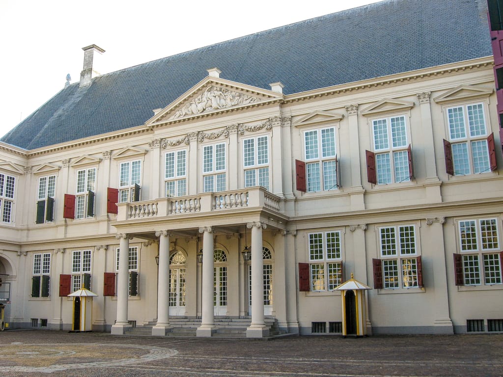a classical building with 4 columns and red shutters on the windows; Noordeinde Palace