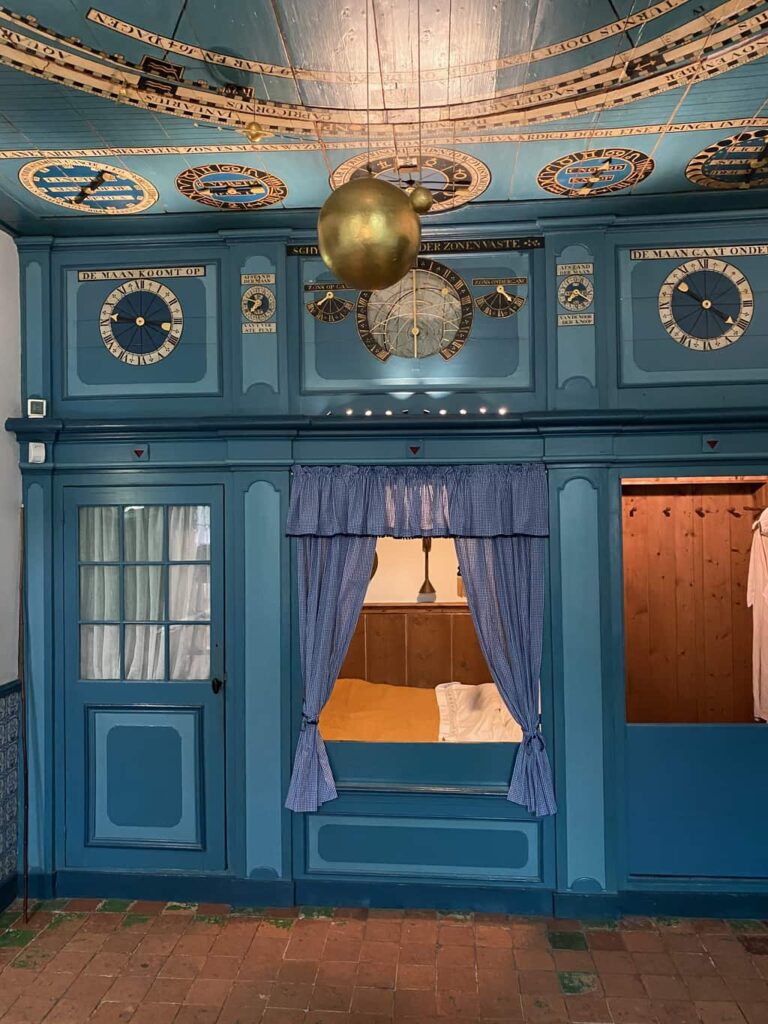 A closet-bed with curtains and golden-like spheres suspended from the ceiling in a room painted in blue shades; the Eise Eisinga Planetarium in Franeker (Friesland)