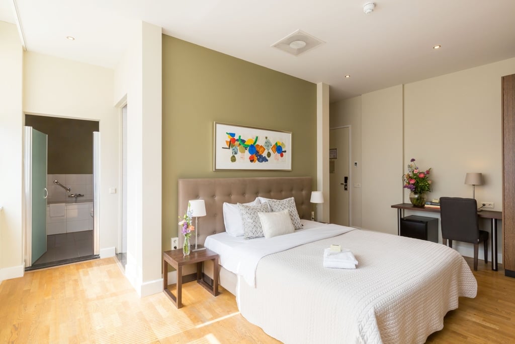 A cozy bedroom at Boutique Hotel Lumiere, Eindhoven, featuring a comfortable bed, a desk, and a television.