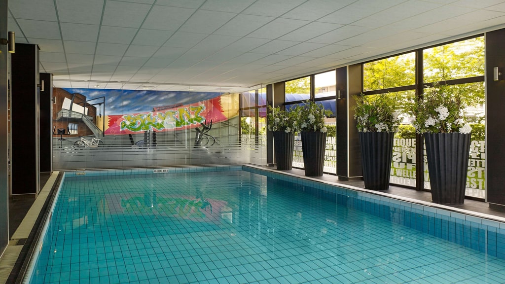 An indoor swimming pool in a building with large windows, offering a serene and refreshing environment, Park Plaza Hotel in Eindhoven